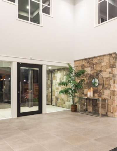 Spacious modern lobby with large windows and stone accent wall. Features a plant, console table with decor, and double doors.